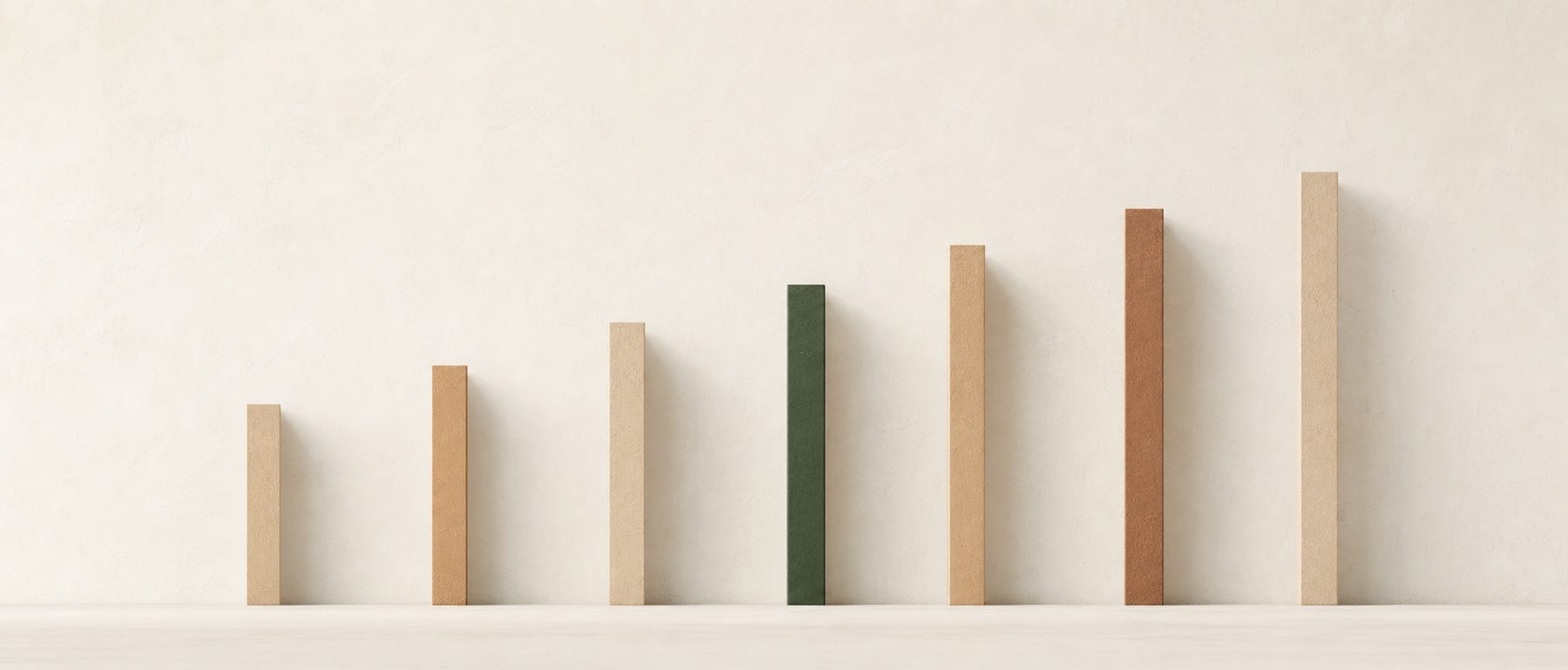 Slender coloured bars of rising height standing against a pale wall, one of them deep green.